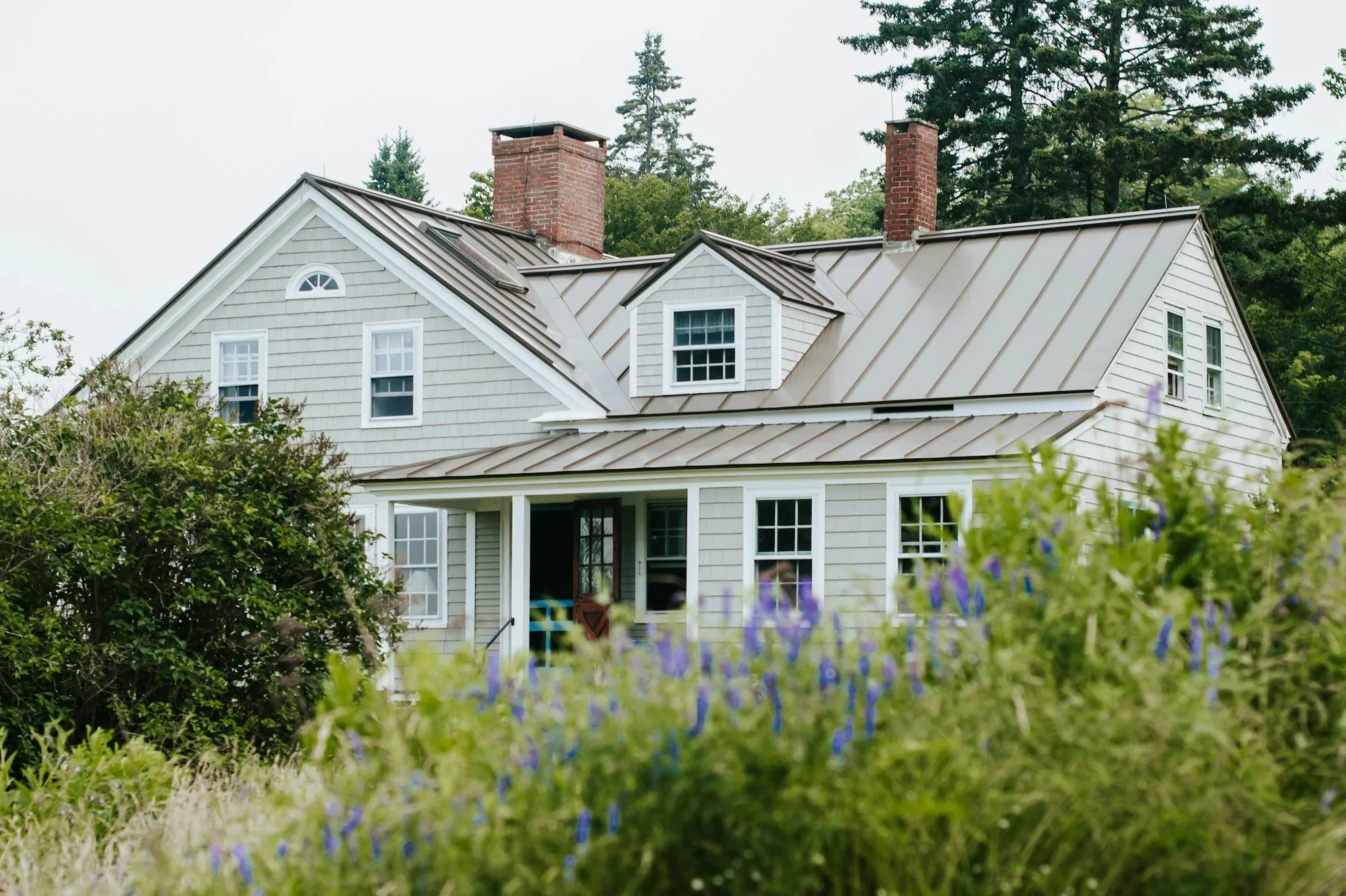 Gray-sided Cape Cod home with a metal roof and dormers