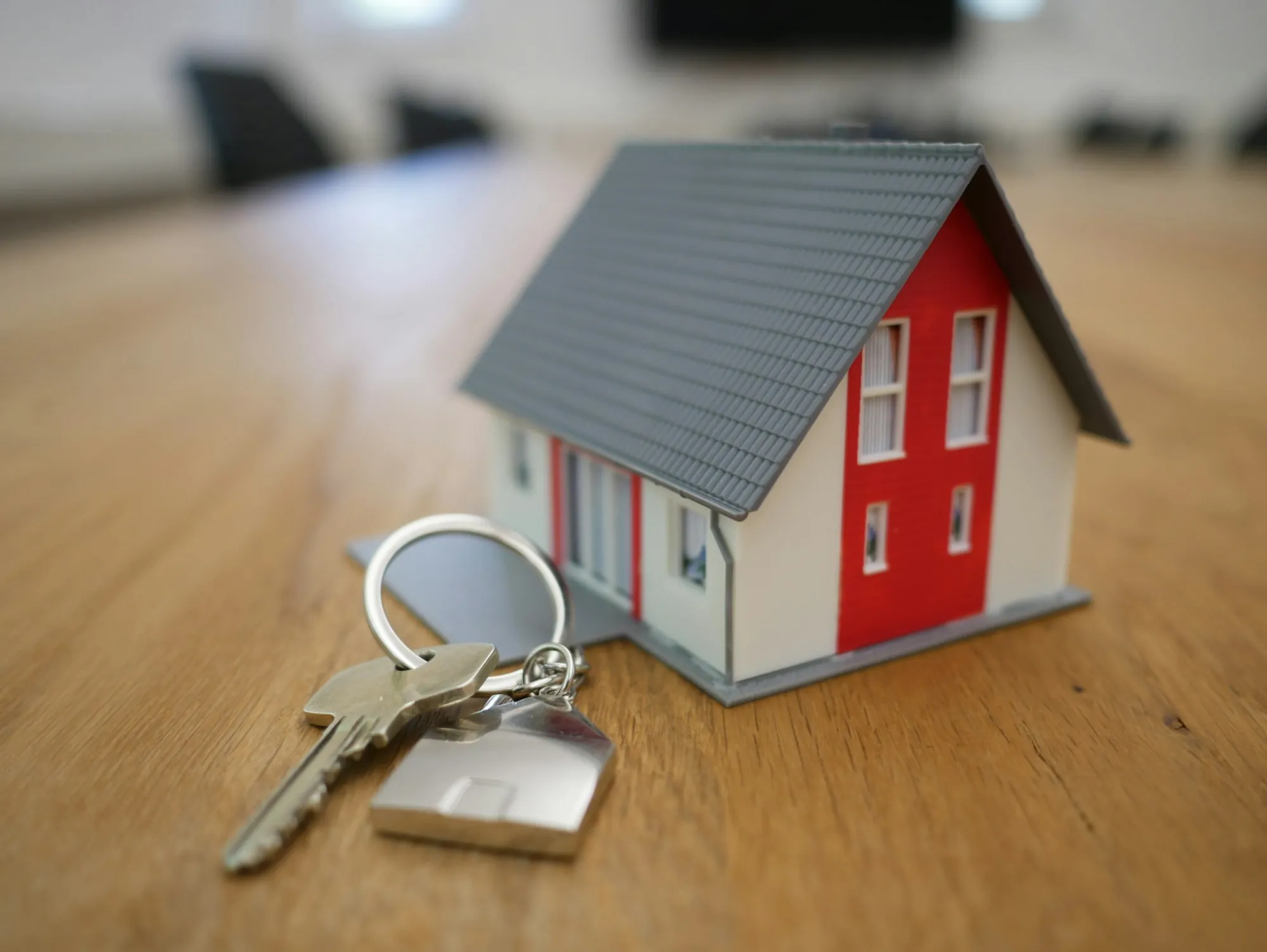 Small model house and a set of keys on a wooden table