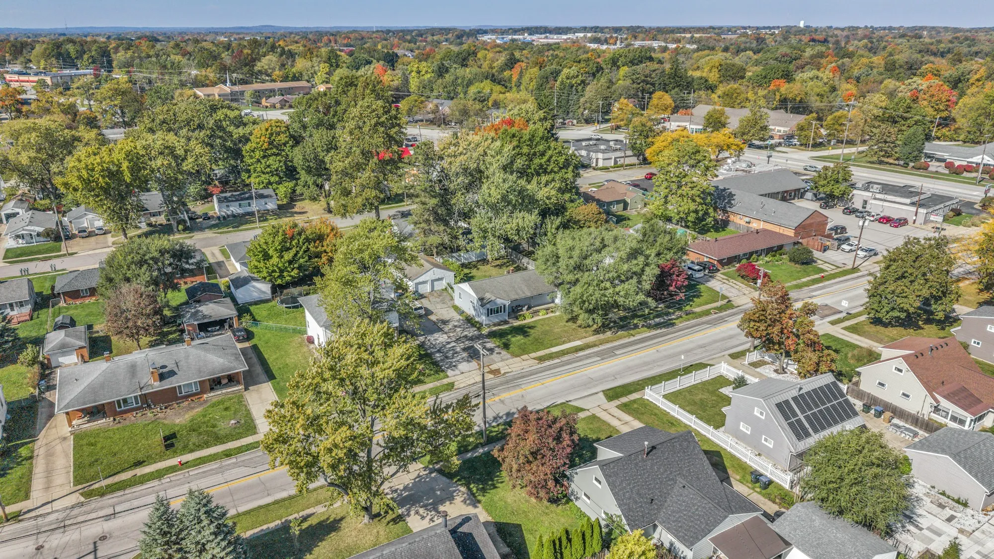Aerial view of a suburban block in fall colors with rooftop solar on a corner house
