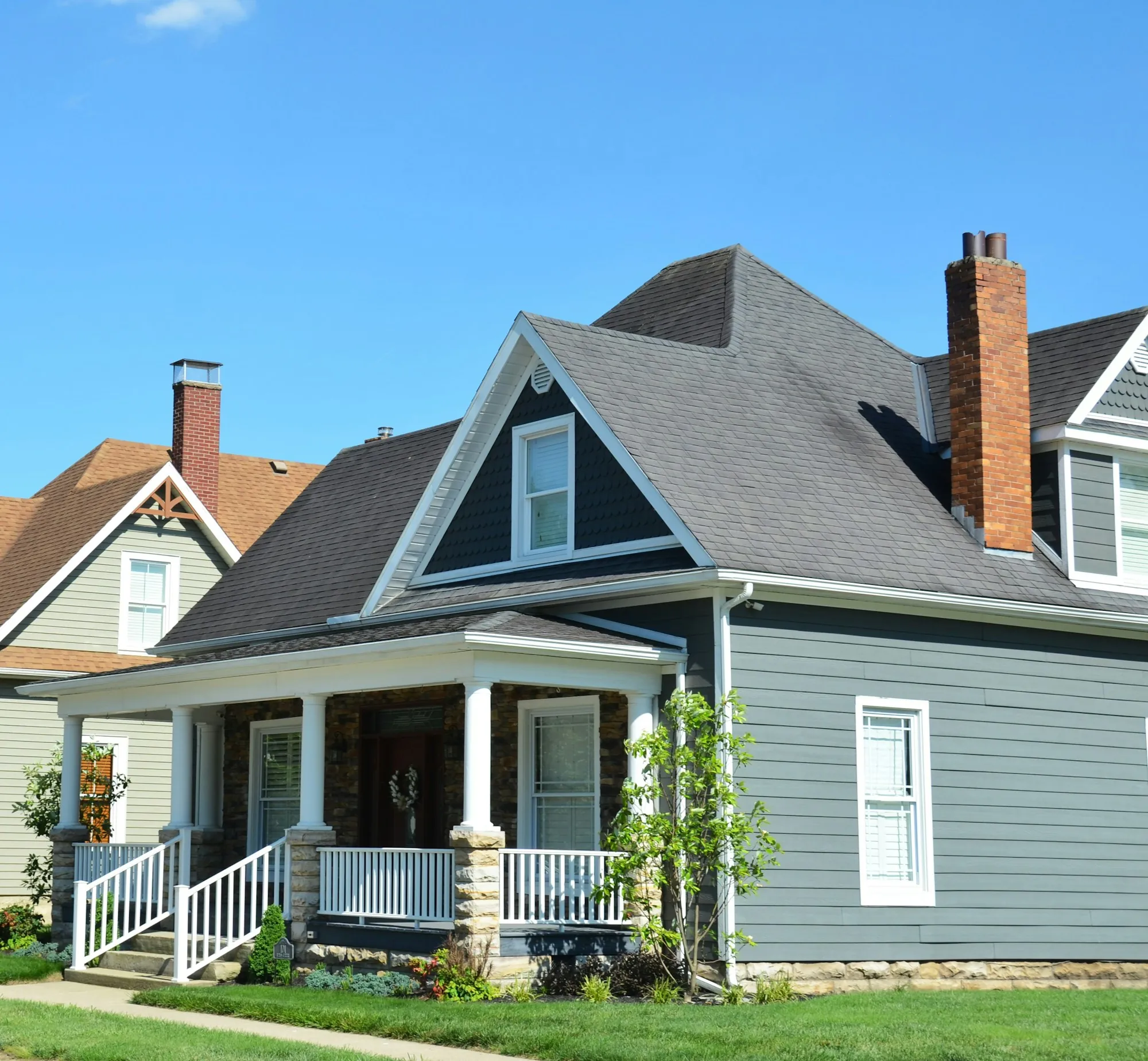 Blue two-story house with a white front porch and brick chimney